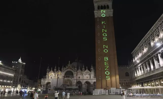 Protesters display a sign "No Kings No Bezos" in St. Mark's Square, in Venice, Italy, Thursday, June 26, 2025. (AP Photo/Antonio Calanni)