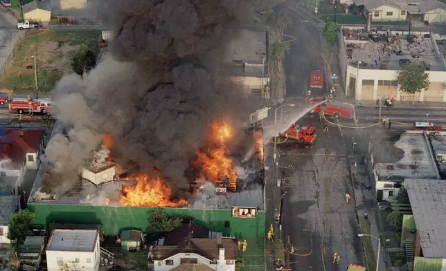 FILE - A fire burns out of control at the corner of 67th Street and West Boulevard in South Central Los Angeles, on April 30, 1992. (AP Photo/Paul Sakuma, File)