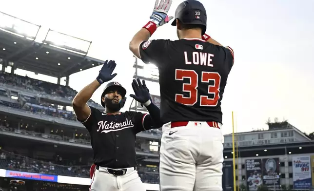 Washington Nationals' Amed Rosario, left, is greeted by Nathaniel Lowe (33) after hitting a solo home run against Chicago Cubs pitcher Matthew Boyd during the seventh inning of a baseball game in Washington, Wednesday, June 4, 2025. (AP Photo/Terrance Williams)