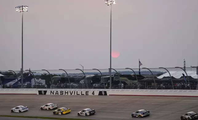 Drivers speed through turn four as the sun sets during a NASCAR Cup Series auto race Sunday, June 1, 2025, in Lebanon, Tenn. (AP Photo/George Walker IV)