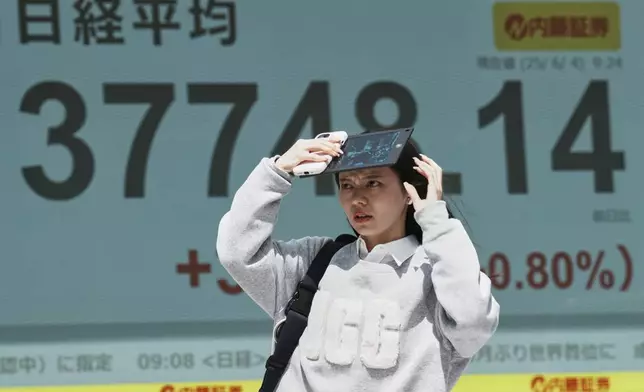 A person walks in front of an electronic stock board showing Japan's Nikkei index at a securities firm Wednesday, June 4, 2025, in Tokyo. (AP Photo/Eugene Hoshiko)