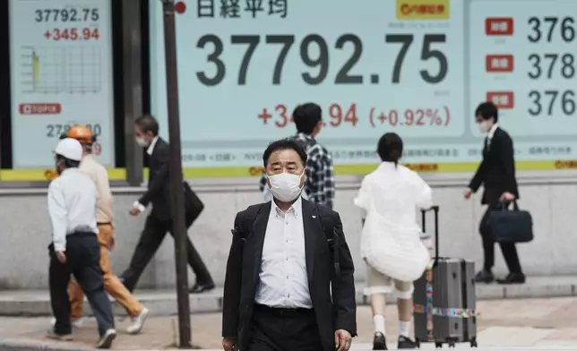 People walk in front of an electronic stock board showing Japan's Nikkei index at a securities firm Wednesday, June 4, 2025, in Tokyo. (AP Photo/Eugene Hoshiko)