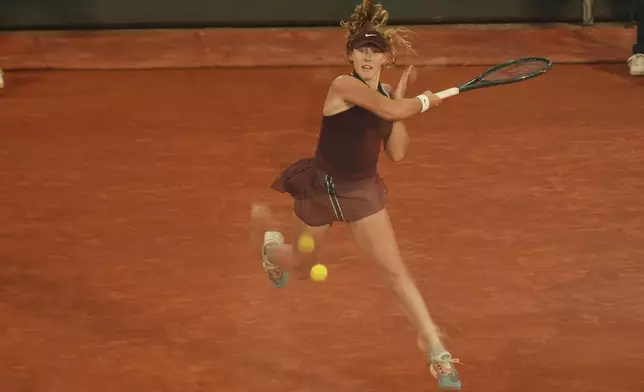Russia's Mirra Andreeva is reflected in a glass as she serves against France's Lois Boisson during their quarterfinal match of the French Tennis Open at the Roland-Garros stadium in Paris, Wednesday, June 4, 2025. (AP Photo/Aurelien Morissard)