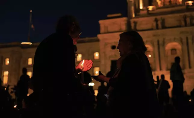 Phil Sandro, left, and Constance Gruen, right, attend a candlelight vigil for former House Speaker Melissa Hortman and her husband Mark, who were fatally shot, at the state Capitol, Wednesday, June 18, 2025, in St. Paul, Minn. (AP Photo/Nikolas Liepins)