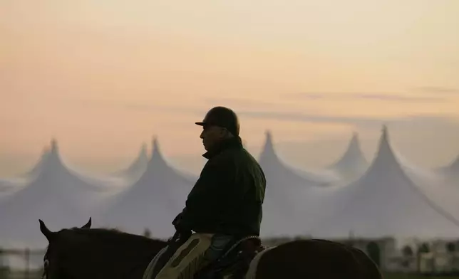 FILE - Trainer D. Wayne Lukas sits atop his horse as he watches morning workouts against the backdrop of a large tent set up in the infield before sunrise at Churchill Downs in Louisville, Ky., April 25, 2009. (AP Photo/Ed Reinke, file)