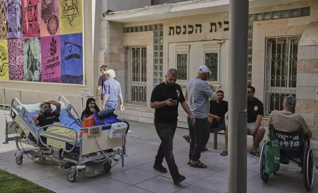 Patients rest outdoors after a building of the Soroka hospital complex was hit by a missile fired from Iran in Be'er Sheva, Israel, Thursday, June 19, 2025. (AP Photo/Leo Correa)