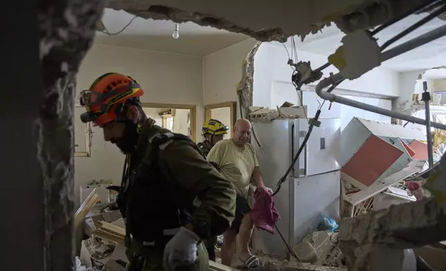 Israeli rescue team evacuate Haim Rasin from his apartment after it was destroyed in an Iranian missile strike in Ramat Gan, Israel, on Thursday, June 19, 2025. (AP Photo/Oded Balilty)