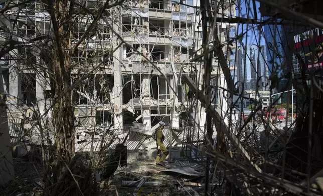 Rescue workers and military personnel inspect the site of a direct hit from an Iranian missile strike in Ramat Gan, Israel, Thursday, June 19, 2025. (AP Photo/Oded Balilty)