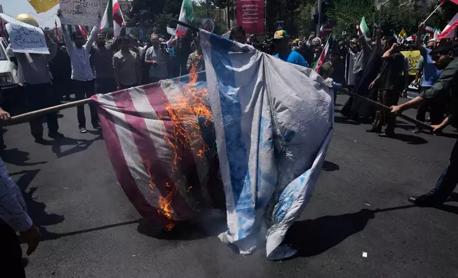 Iranian protestors burn representations of the Israeli and U.S. flags during a protest to condemn Israeli attacks on multiple cities across Iran, after the Friday prayers ceremony in Tehran, Iran, Friday, June 20, 2025. (AP Photo/Vahid Salemi)