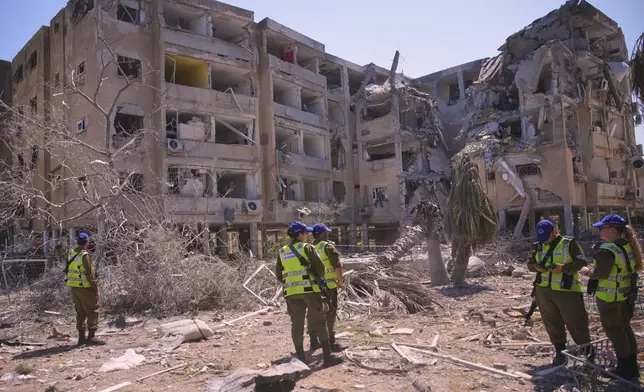 Israeli security forces stand next to a destroyed building that was hit by a missile fired from Iran, in Holon, near Tel Aviv, Israel, Thursday, June 19, 2025. (AP Photo/Ohad Zwigenberg)