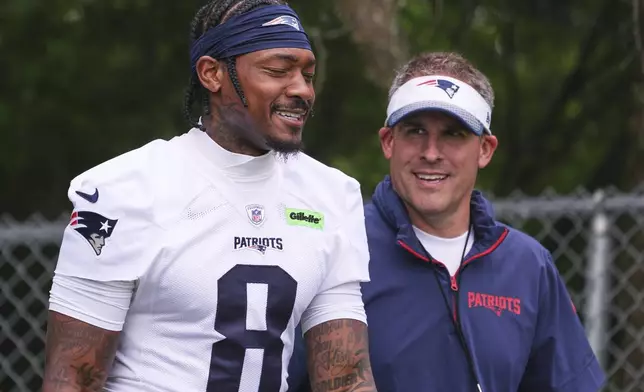 New England Patriots wide receiver Stefon Diggs, left, smiles while walking with offensive coordinator Josh McDaniels during an NFL football practice, Monday, June 9, 2025, in Foxborough, Mass. (AP Photo/Charles Krupa)