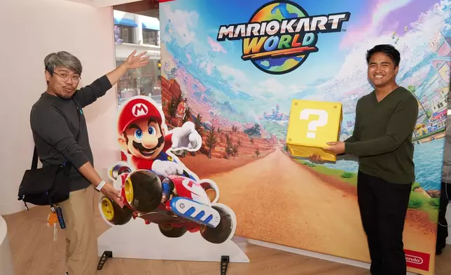 In this photo provided by Nintendo of America, fans take photos ahead of purchasing their Nintendo Switch 2 system and Mario Kart World. Nintendo Switch 2, the seamlessly social, all-in-one Nintendo platform, is available now.