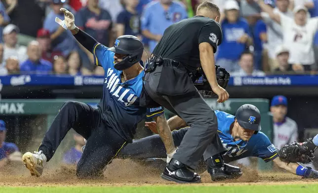Philadelphia Phillies Nick Castellanos, left, and J.T. Realmuto, right, score on an RBI single by Bryson Stott in the seventh inning of a baseball game against the New York Mets, Friday, June 20, 2025, in Philadelphia. (AP Photo/Laurence Kesterson)