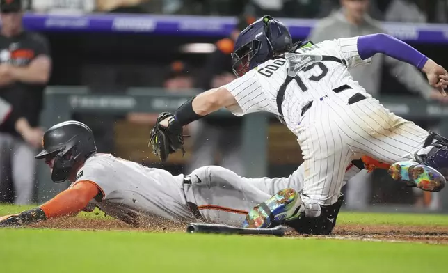 San Francisco Giants' Casey Schmitt, left, scores on a bunt single hit by Tyler Fitzgerald as Colorado Rockies catcher Hunter Goodman applies a late tag in the eighth inning of a baseball game Wednesday, June 11, 2025, in Denver. (AP Photo/David Zalubowski)