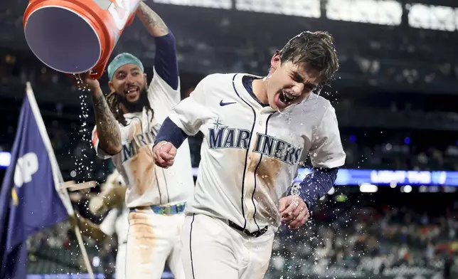 Seattle Mariners' Cole Young is dunked with water by J.P. Crawford after reaching first on a fielder's choice that allowed Miles Mastrobuoni to score the walk-off run during the 11th inning of a baseball game against the Minnesota Twins Saturday, May 31, 2025, in Seattle. (AP Photo/Ryan Sun)