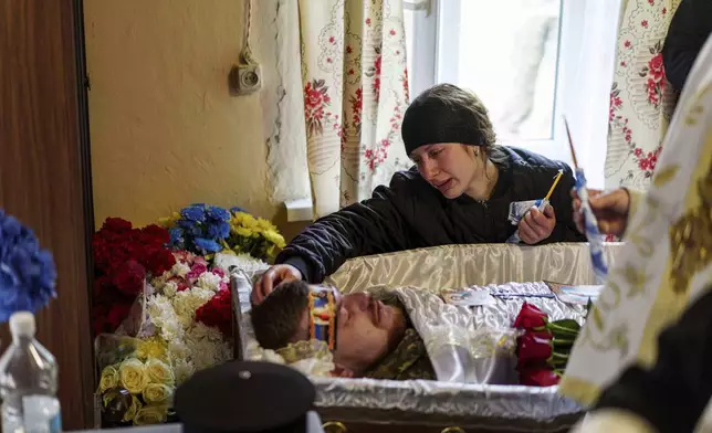 Olena cries at the coffin of her husband, Dmytro Shapovalov, a Ukrainian serviceman, during his funeral ceremony in Yosypivka village, Vinnytsia region, Ukraine, on Friday, June 13, 2025. (AP Photo/Evgeniy Maloletka)