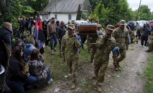 An honor guard carries the coffin of Dmytro Shapovalov, a Ukrainian serviceman, during his funeral ceremony in Yosypivka village, Vinnytsia region, Ukraine, on Friday, June 13, 2025. (AP Photo/Evgeniy Maloletka)
