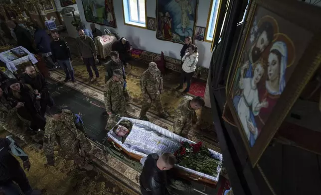 An honor guard carries the coffin of Dmytro Shapovalov, a Ukrainian serviceman, during his funeral ceremony at the church in Yosypivka village, Vinnytsia region, Ukraine, on Friday, June 13, 2025. (AP Photo/Evgeniy Maloletka)