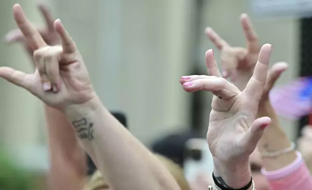 Supporters of Karen Read make the American Sign Language sign for "I Love You" as she leaves the courthouse at the start of the third day of jury deliberations in Read's trial at Norfolk Superior Court, Wednesday, June 18, 2025, in Dedham, Mass. (AP Photo/Josh Reynolds)