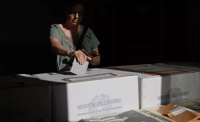 A woman casts her ballots on referendums on citizenship and job protections, at a polling station in Rome, Sunday, June 8, 2025. (Cecilia Fabiano/LaPresse via AP)