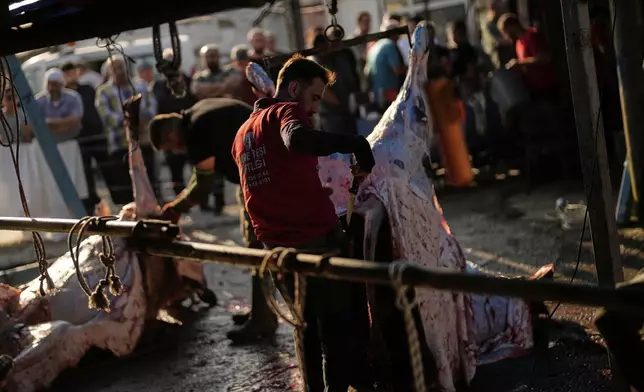 Men cut meat from cows slaughtered for sacrifice on the first day of Eid al-Adha, in Istanbul, Friday, June 6, 2025. (AP Photo/Khalil Hamra)