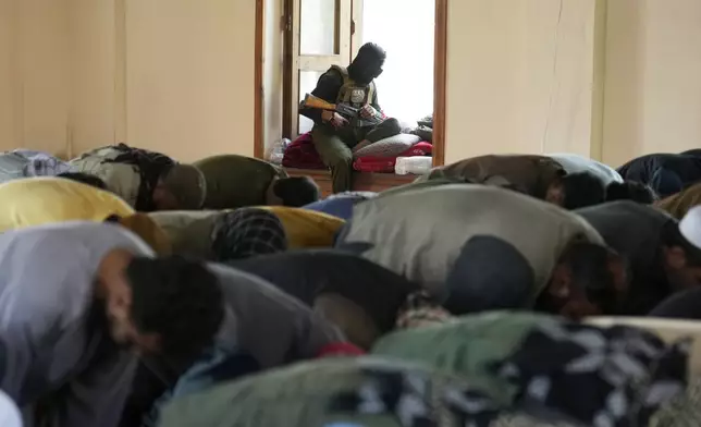 Afghan Muslims perform Eid al-Adha prayer while a Taliban fighter stands guard in the Shah-Do Shamshira Mosque in Kabul, Afghanistan, Saturday, June 7, 2025. (AP Photo/Ebrahim Noroozi)