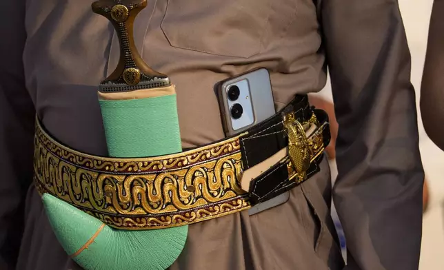 A boy of the Muslim community in Romania holds his phone in a traditional belt during Eid al-Adha prayers at the Dinamo stadium in Bucharest, Romania, Friday, June 6, 2025. (AP Photo/Andreea Alexandru)