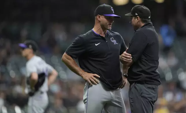 Colorado Rockies interim manager Warren Schaeffer, left, talks with an umpire, right, during the fifth inning of a baseball game against the Milwaukee Brewers, Friday, June 27, 2025, in Milwaukee. (AP Photo/Aaron Gash)