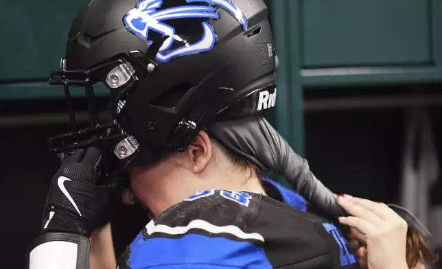 Detroit Prowl's Kelly Zetting gets help pulling her helmet over her hair before an AWFL women's football game against the Lansing Legacy in Allen Park, Mich., Saturday, May 10, 2025. (AP Photo/Paul Sancya)
