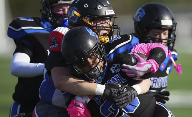 Detroit Prowl running back Bugg Patman (25) is tackled by Lansing Legacy's Sarah Kowalczyk during an AWFL women's football game in Allen Park, Mich., Saturday, May 10, 2025. (AP Photo/Paul Sancya)