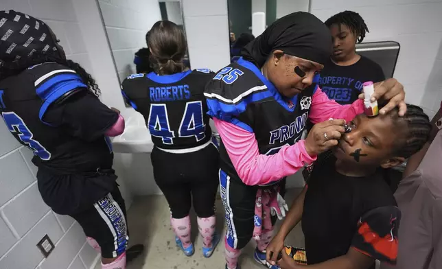Detroit Prowl's Bugg Patman applies face paint to Jahi Tillman, as they prepare for an AWFL women's football game against the Lansing Legacy, in Allen Park, Mich., Saturday, May 10, 2025. (AP Photo/Paul Sancya)