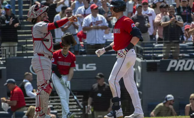 Cleveland Guardians' Lane Thomas, right, touches home plate after hitting a three-run home run off Cincinnati Reds relief pitcher Joe La Sorsa as Jose Trevino stands by during the sixth inning of a baseball game, Wednesday, June 11, 2025, in Cleveland. (AP Photo/Phil Long)