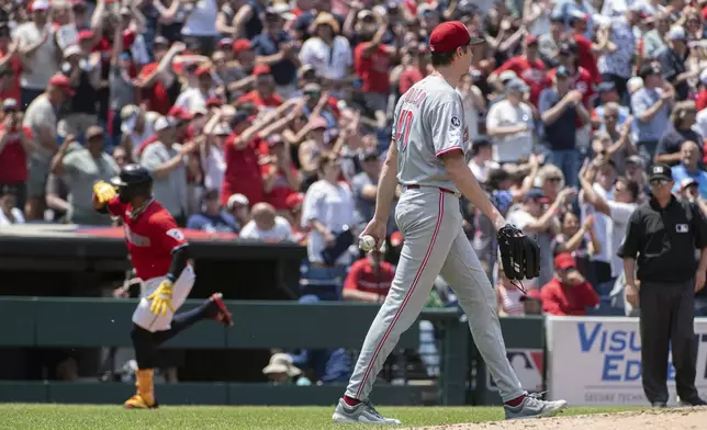Cincinnati Reds starting pitcher Nick Lodolo, front, walks back to the mound as Cleveland Guardians' Carlos Santana, rear, rounds the bases after hitting a three-run home run during the third inning of a baseball game, Wednesday, June 11, 2025, in Cleveland. (AP Photo/Phil Long)