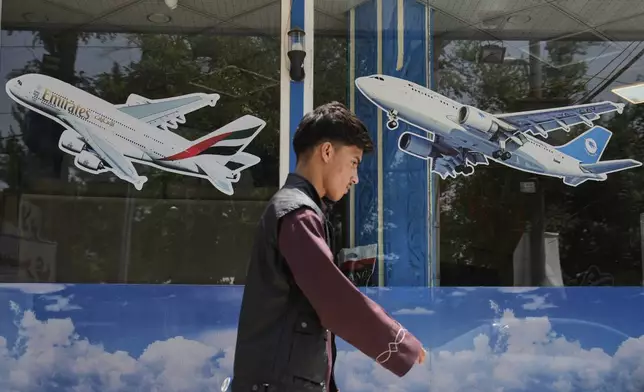 An Afghan man passes in front of an air travel agency in Kabul, Afghanistan, Thursday, June 5, 2025. (AP Photo/Ebrahim Noroozi)