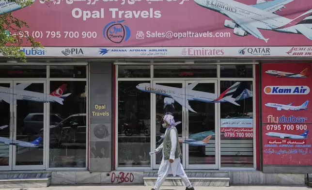An Afghan person passes in front of an air travel agency in Kabul, Afghanistan, Thursday, June 5, 2025. (AP Photo/Ebrahim Noroozi)