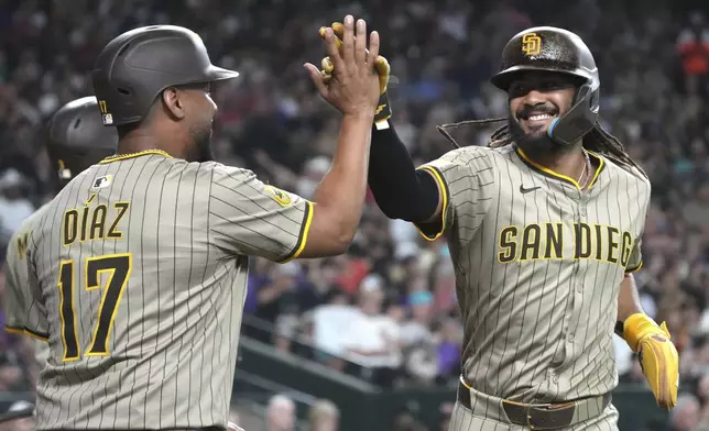 San Diego Padres' Fernando Tatis Jr., right, celebrates with Elias Díaz (17) after scoring on a double hit by Manny Machado in the seventh inning during a baseball game against the Arizona Diamondbacks, Saturday, June 14, 2025, in Phoenix. (AP Photo/Rick Scuteri)