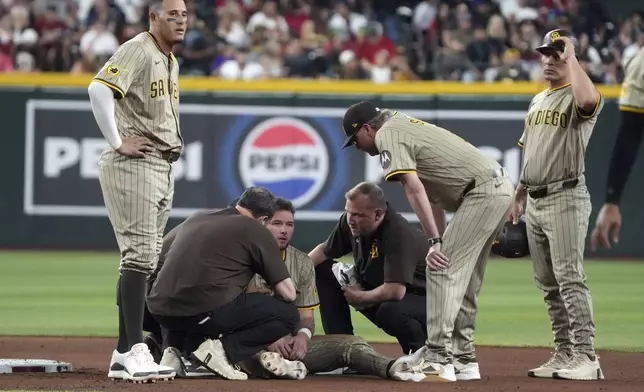 San Diego Padres' Jackson Merrill, third from left, is helped by trainers after being tagged out by Arizona Diamondbacks second baseman Ketel Marte (not shown) while trying to steal second in the seventh inning during a baseball game, Saturday, June 14, 2025, in Phoenix. (AP Photo/Rick Scuteri)