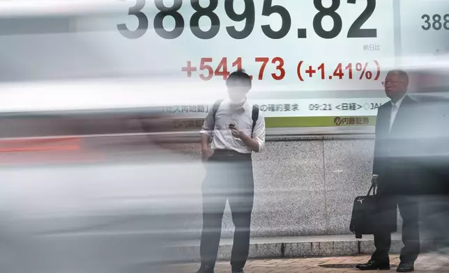 People stand in front of an electronic stock board showing Japan's Nikkei index at a securities firm Tuesday, June 24, 2025, in Tokyo. (AP Photo/Eugene Hoshiko)
