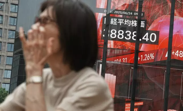 A person stands in front of an electronic stock board showing Japan's Nikkei index at a securities firm Tuesday, June 24, 2025, in Tokyo. (AP Photo/Eugene Hoshiko)