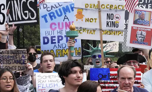 Demonstrators carrying signs stand near the White House during a protest taking place on the day of a military parade commemorating the Army's 250th anniversary, coinciding with President Donald Trump's 79th birthday, Saturday, June 14, 2025, in Washington. (AP Photo/Alex Brandon)