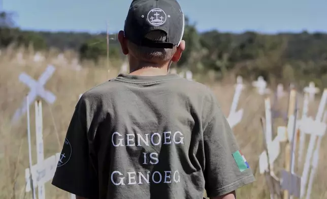Jano de Lange, wearing a shirt that reads, "Enough is enough," observes white crosses at the Witkruis Monument, near Polokwane, South Africa, May 24, 2025. (AP Photo/Mogomotsi Magome)