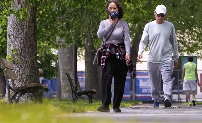 A woman wears a protective mask while walking along the banks of the Merrimack River, Wednesday, June 4, 2025, in Lowell, Mass. (AP Photo/Charles Krupa)