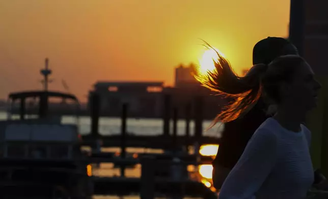 People run along the East River in the Brooklyn borough of New York, Wednesday, June 4, 2025, during an air quality alert issued for the New York region due to wildfire smoke from Canada. (AP Photo/Heather Khalifa)