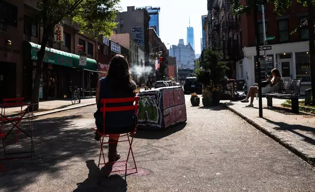 An air quality alert has been issued for the New York region due to wildfire smoke from Canada as a person smokes while sitting in the street, Wednesday, June 4, 2025, in New York. (AP Photo/Heather Khalifa)