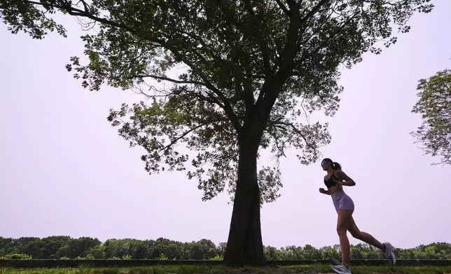 A woman runs along the banks of the Merrimack River, Wednesday, June 4, 2025, in Lowell, Mass. (AP Photo/Charles Krupa)