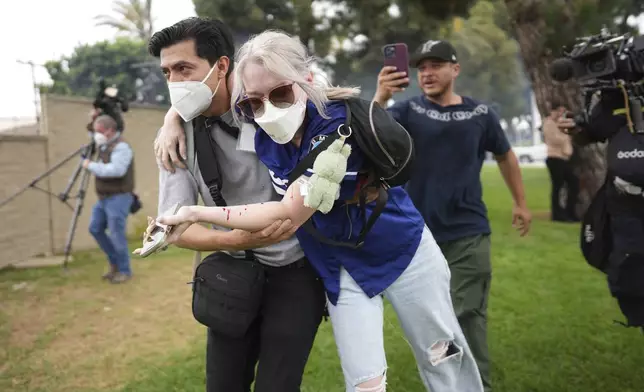 A man helps an injured woman during a protest in the Paramount section of Los Angeles, Saturday, June 7, 2025, after federal immigration authorities conducted operations. (AP Photo/Eric Thayer)