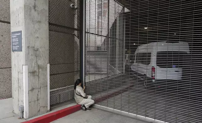 A woman watches as federal immigration authorities arrive with detainees at the Federal Building after conducting operations in Los Angeles, Saturday, June 7, 2025. (AP Photo/Eric Thayer)