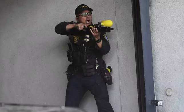 A Department of Homeland Security officer reacts after shooting pepper balls during a protest at the U.S. Department of Justice Federal Bureau of Prisons after federal immigration authorities conducted an operation on Friday, June 6, 2025, in Los Angeles. (AP Photo/Jae C. Hong)