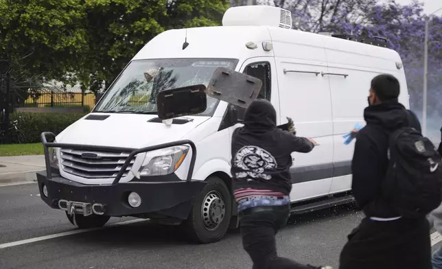 Protesters throw objects as law enforcement drive a van past during a protest in the Paramount section of Los Angeles, Saturday, June 7, 2025, after federal immigration authorities conducted operations. (AP Photo/Eric Thayer)