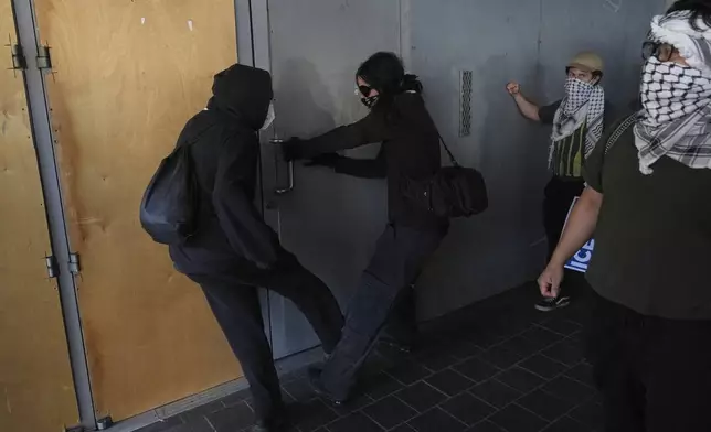 Protesters kick a door at the U.S. Department of Justice Federal Bureau of Prisons during a protest after federal immigration authorities conducted an operation on Friday, June 6, 2025, in Los Angeles. (AP Photo/Jae C. Hong)